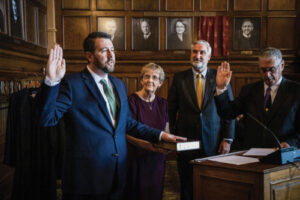 Newton Circuit Judge Daniel Molter administers the oath of office to his son, Hon. Derek Molter, with mother, Kate Molter, holding the bible, and Gov. Eric Holcomb standing in participation after passing his duties to swear in the new justice to his proud father.